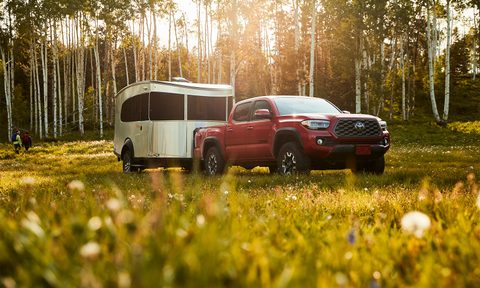 Red Toyota Tacoma towing an Airstream Basecamp throw a grassy field.