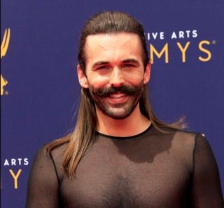 Jonathan Van Ness standing on the red carpet in front of a blue step and repeat at the Creative Arts Emmys 2018