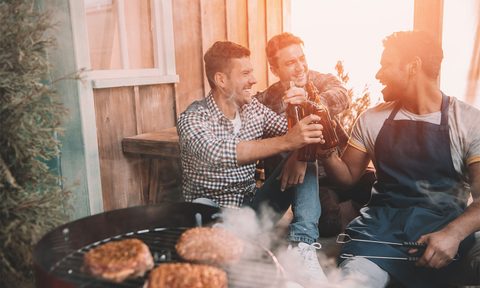 Friends enjoying beers by the barbecue.