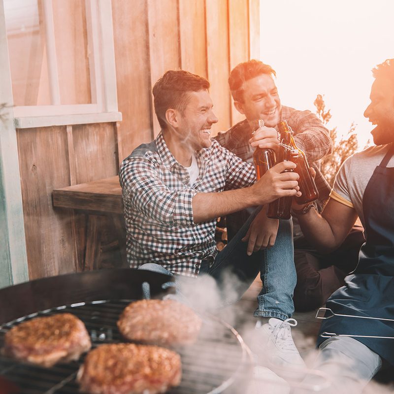 Friends enjoying beers by the barbecue.