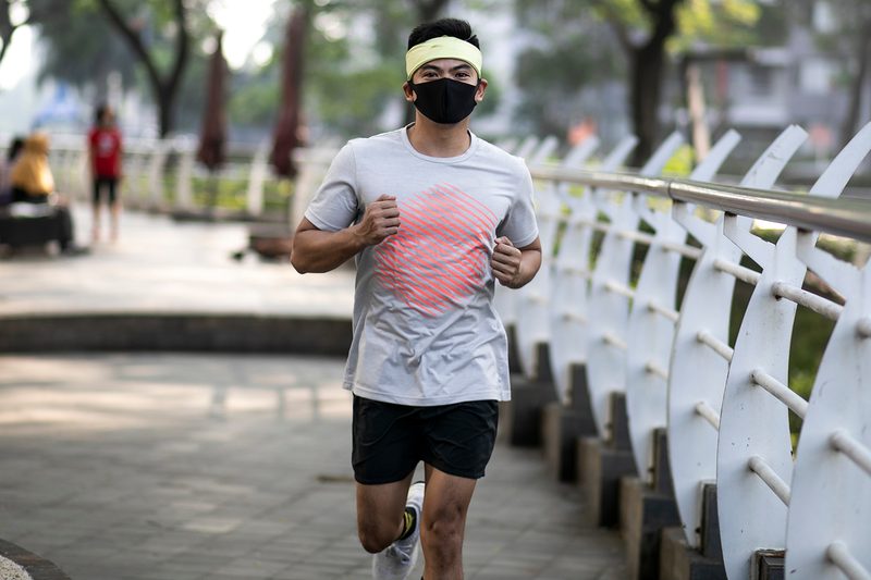 Young man running with face mask.