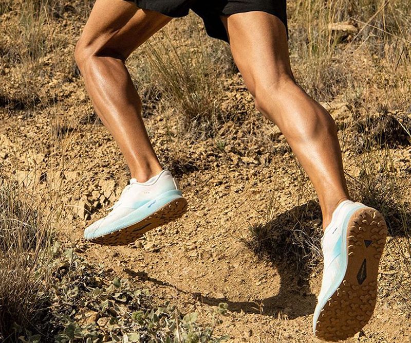A man dressed in a pair of running shoes running a trail.