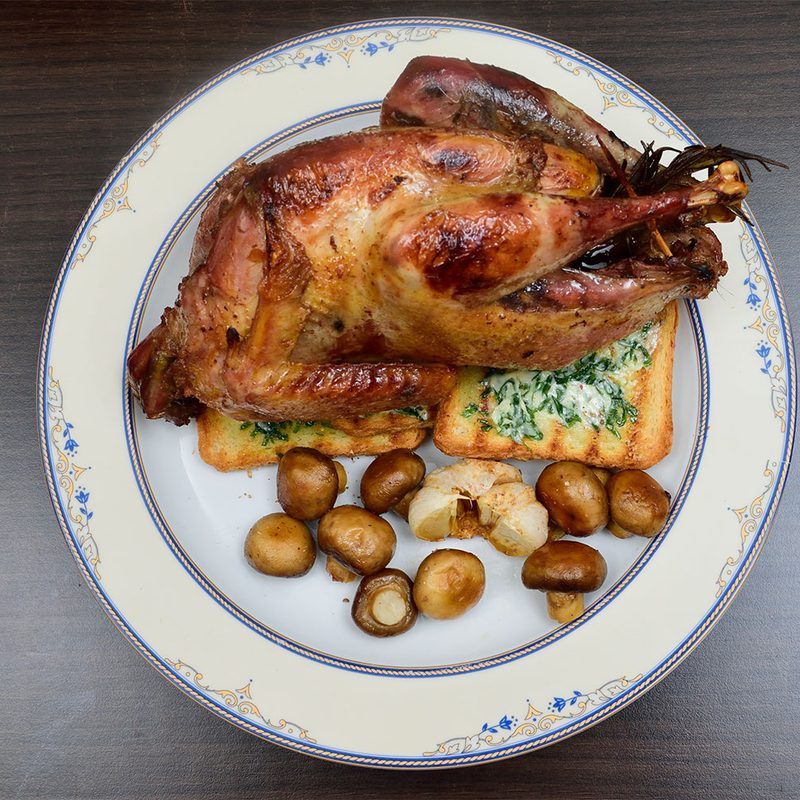 Pheasant on a plate with bread and potatoes.