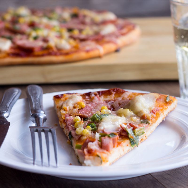 A slice of pizza on a plate next to a knife and fork