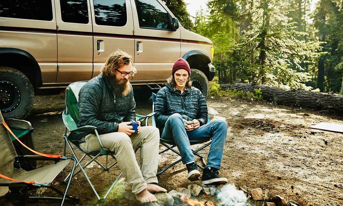 Two men in camping chars by a campfire
