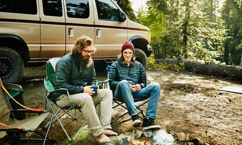 Two men in camping chars by a campfire