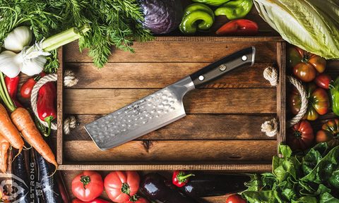 Chef's knife on a cutting board with food around it