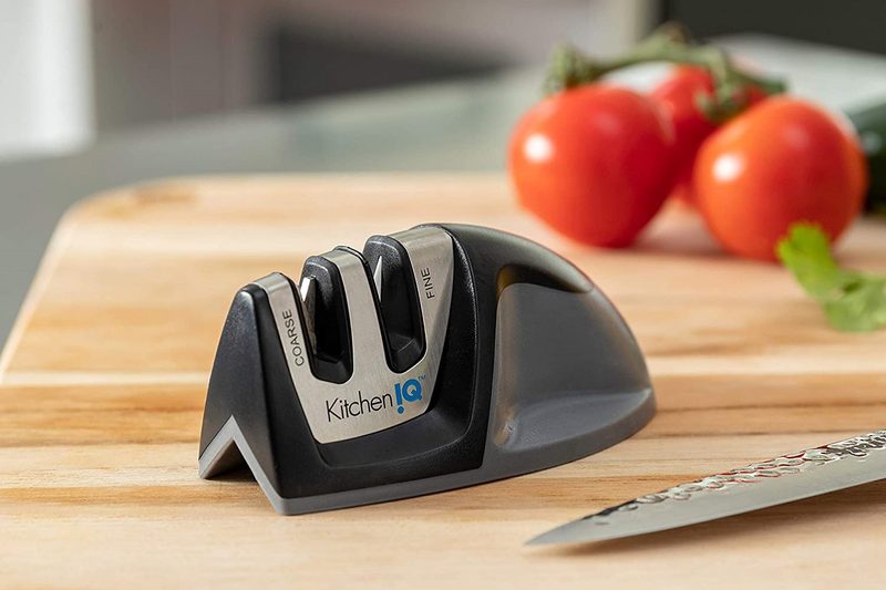 a ktichen iq knife sharpener sitting on a counter with tomatoes in the background.