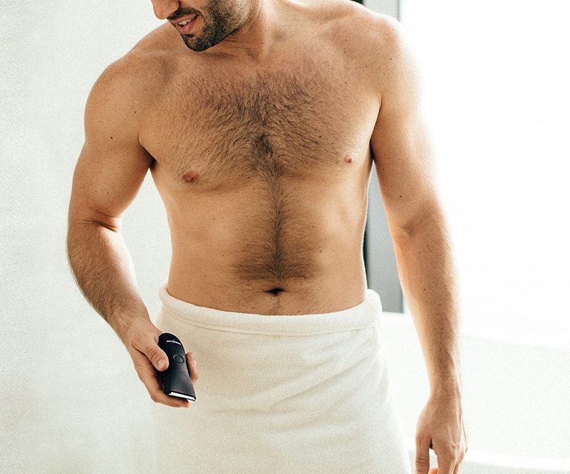 Shirtless man wrapped with towel on the waist down, holding a razor.