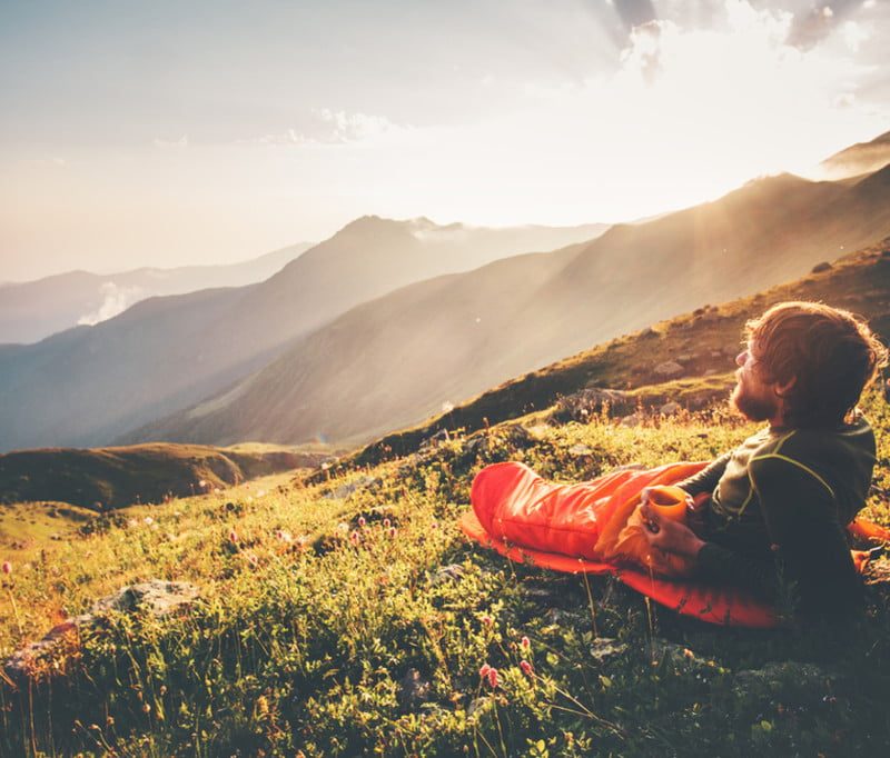 Man reclining on hillside in sleeping bag