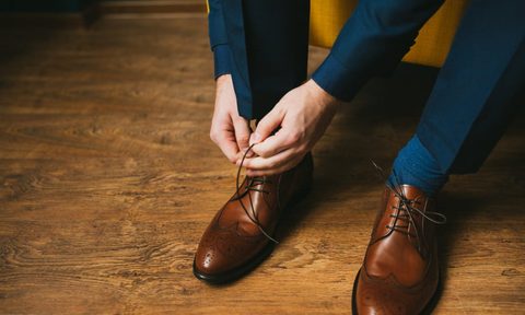 A man in a suit lacing his shoes