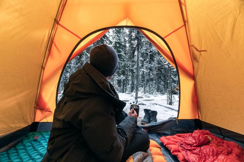 Man drinking coffee in his tent in the cold