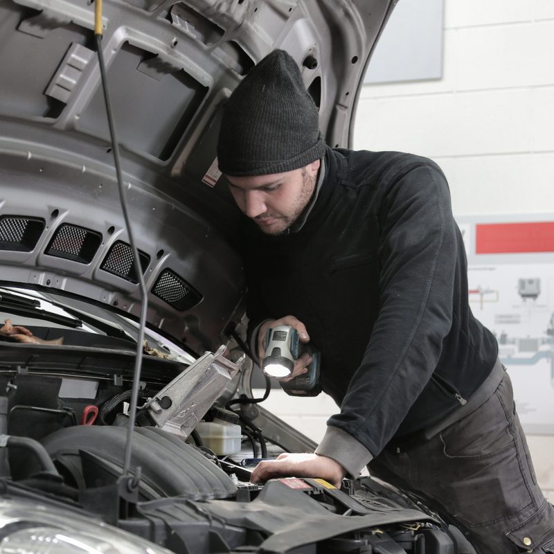 Car mechanic checking car engine.