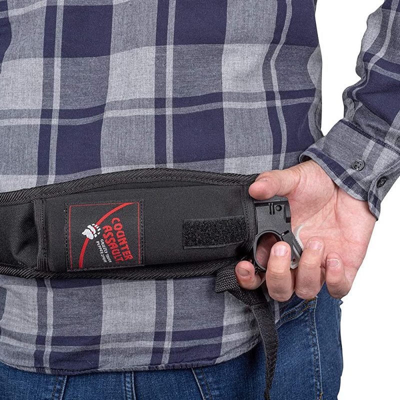 Man's back with his hand on the release of Counter Assault Neoprene Trailrunner Bear Spray in a holster belt.
