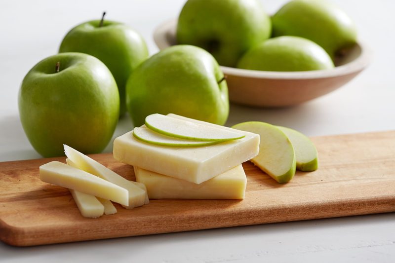 Granny Smith Apples with cheese on a wooden cutting board.