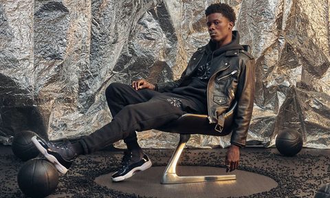 A man in black leather jacket and pants sitting on a chair.