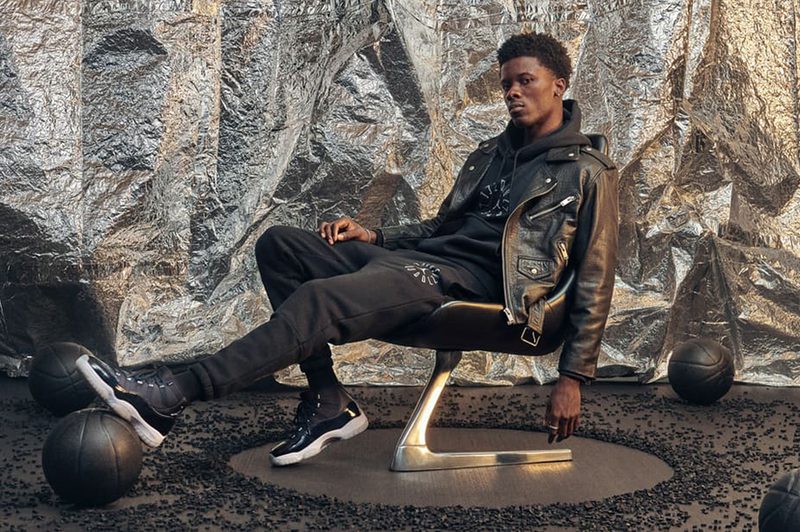 A man in black leather jacket and pants sitting on a chair.