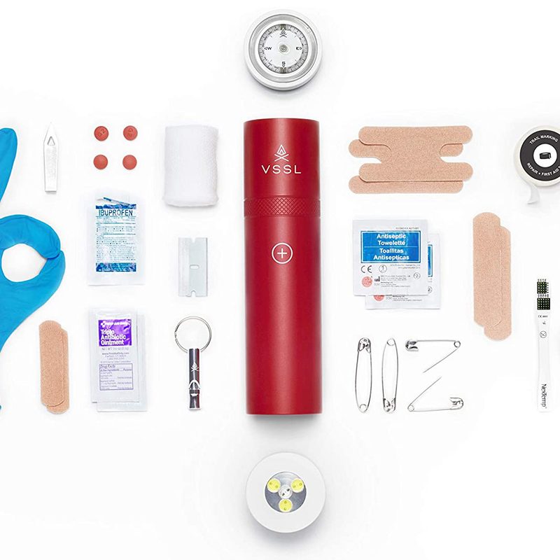 A red VSSL Compact Adventure First Aid Kit with its contents displayed on white background.