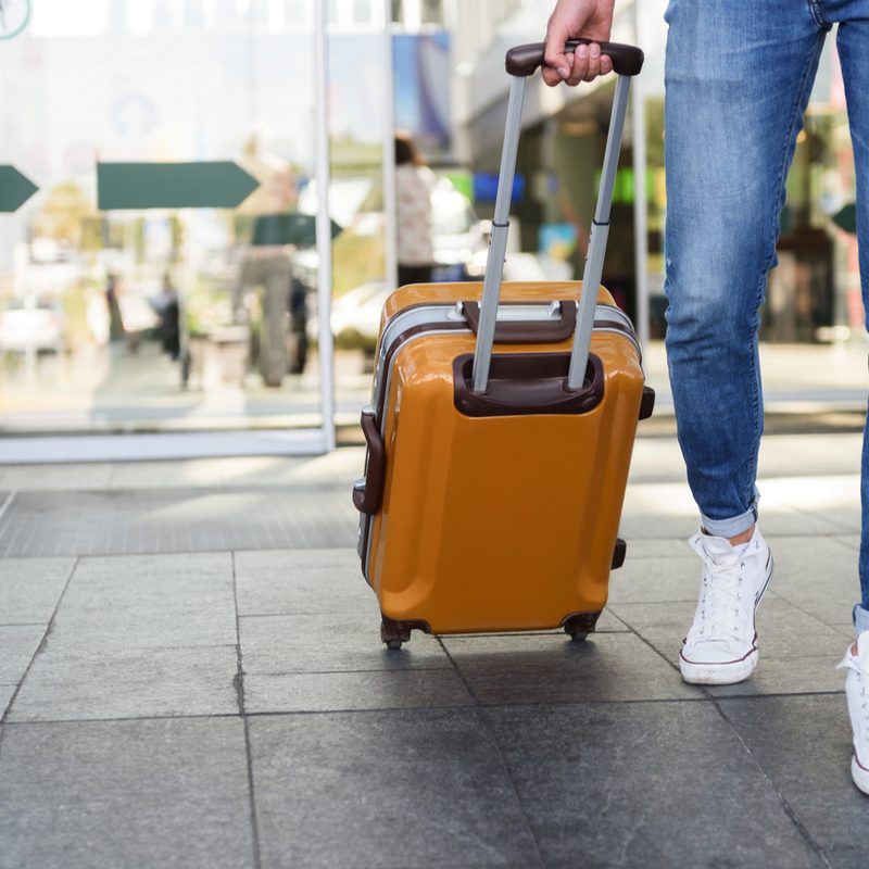A person pulling a carry-on suitcase through the airport