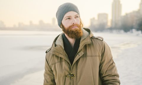 best shearling jackets close up caucasian young male red hair and beard in a hat park coat posing winter model against backgr