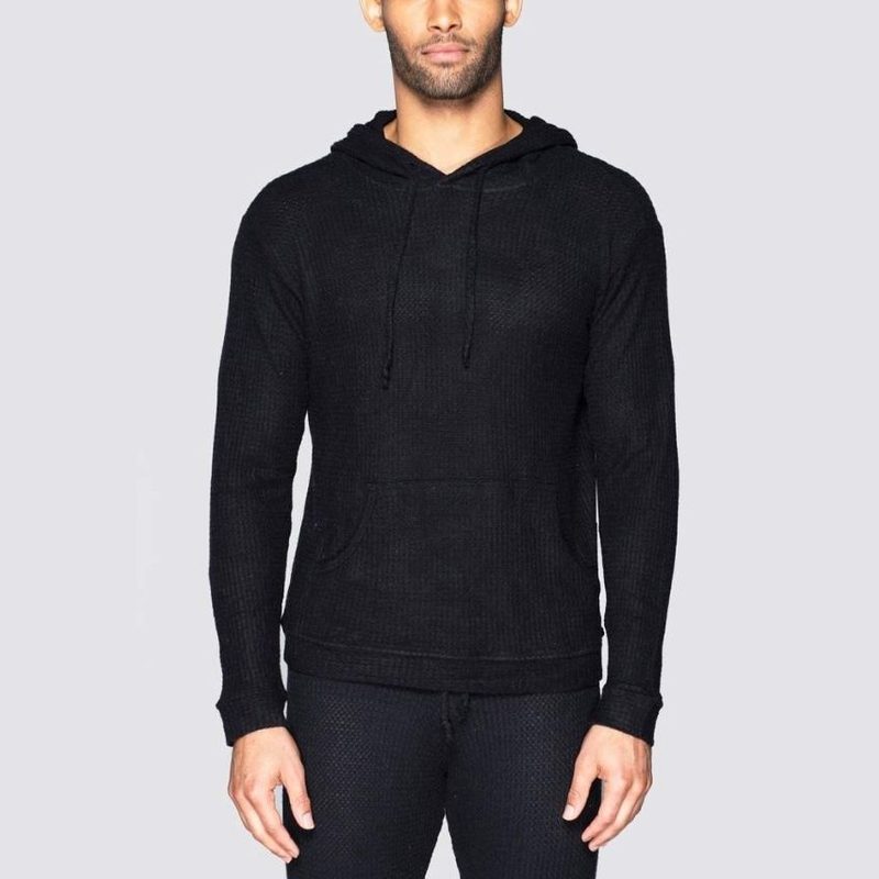 A male model wearing a black Bleusalt Unisex Waffle Skater Hoodie.