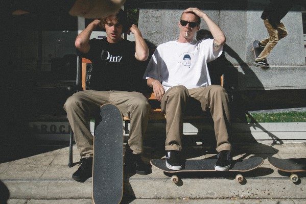 Two men with skateboards sitting on bench