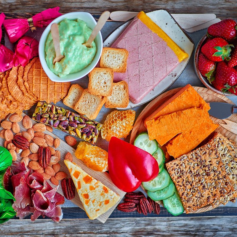 Charcuterie board with avocado dip, Leicester cheese, Wensleydale cheese, honey, cucumber, and more