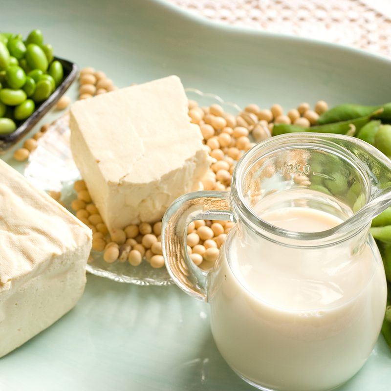 Assorted soy-based foods, including edamame, tofu, soybeans, and soy milk.