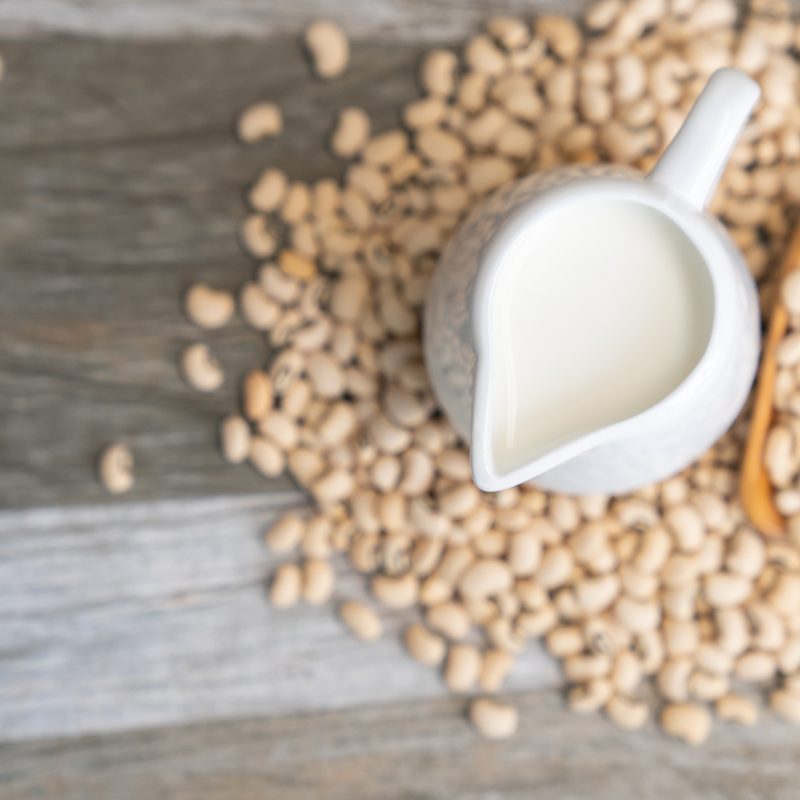 Soy milk and soybeans on a wooden background.