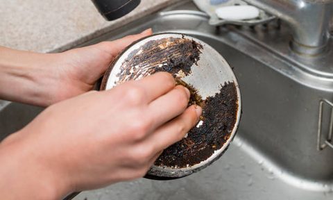 Washing the bottom of a dirty pot.