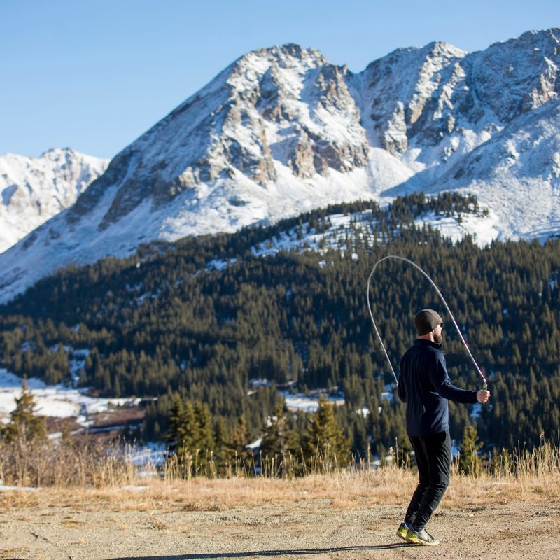 Man jumping rope outside with a mountain in the background