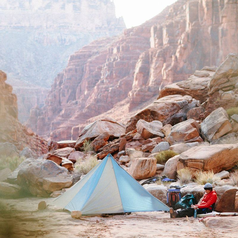 Man sitting in front of an Outdoor Research tent.