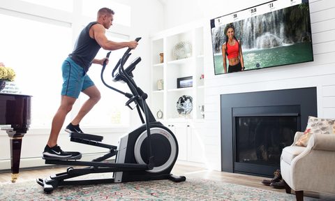 A man working out on the ProForm Carbon EL Elliptical while watching TV.