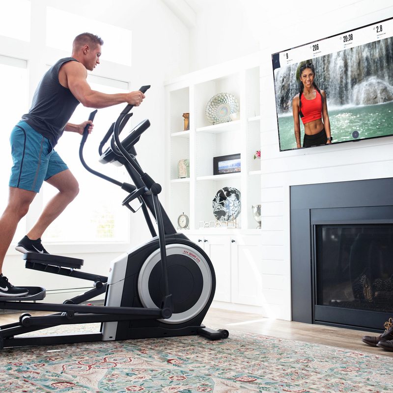 A man working out on the ProForm Carbon EL Elliptical while watching TV.