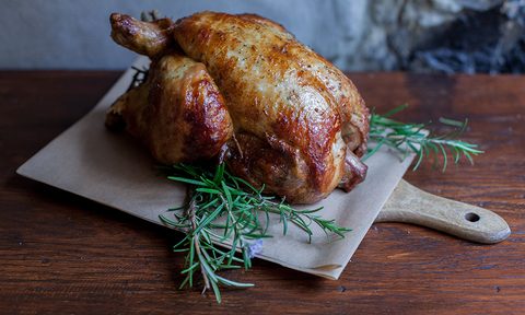 Close-up of a roasted chicken on a cutting board at a table