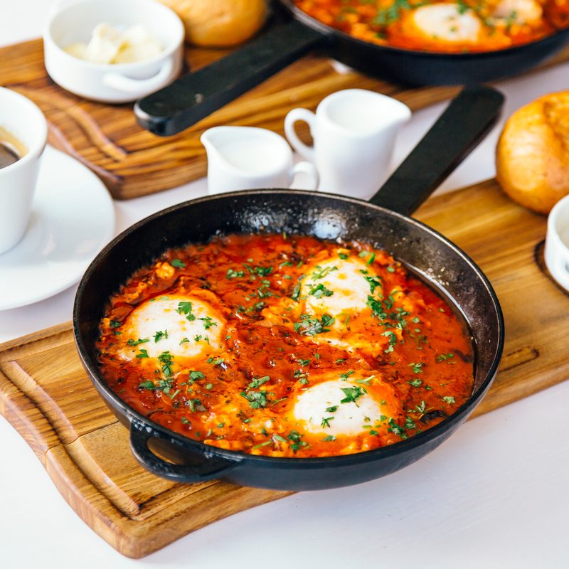 Breakfast shakshuka with tomato sauce and eggs and coffee