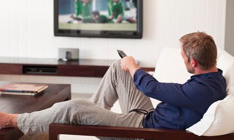 Man changing TV channels with remote control