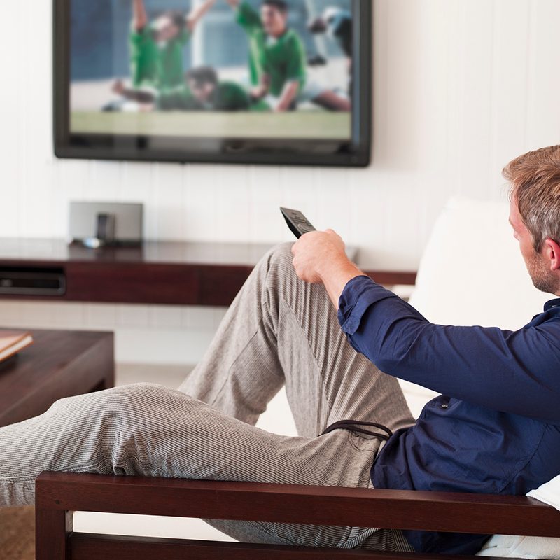 Man changing TV channels with remote control