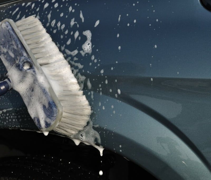 Cleaning a car with a long-handled brush