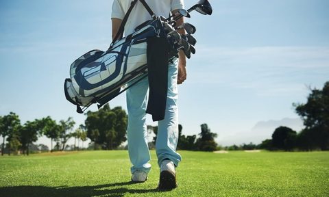 A golfer carrying their bag on the course.
