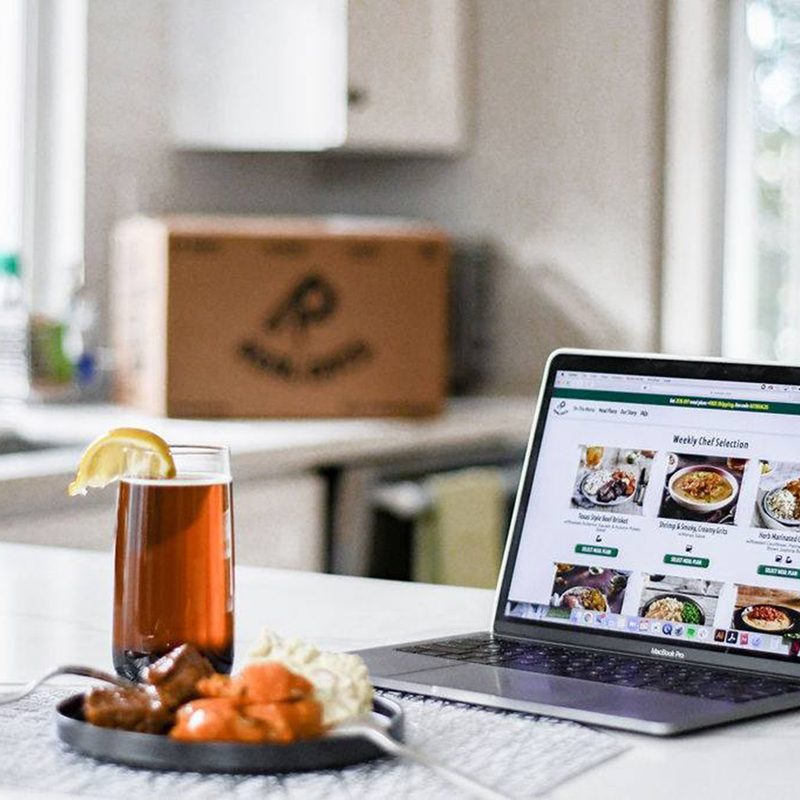 A healthy dish and a drink with towel and laptop on a kitchen counter.