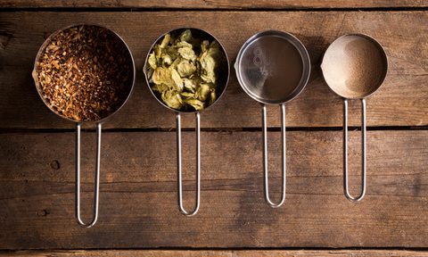 An overhead shot of a collection of basic home-brew beer ingredients, sitting on a rustic wooden background