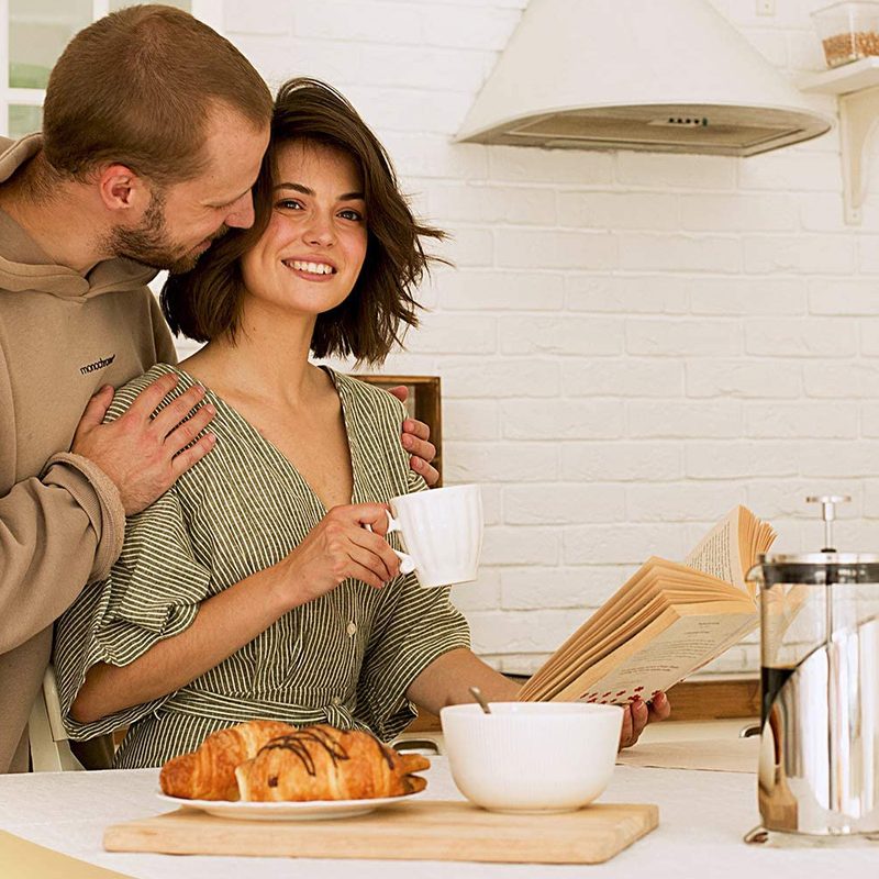 Couple in the kitchen with a French press on the counter.