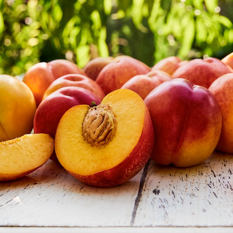 Ripe peaches with leaves on the old wooden table