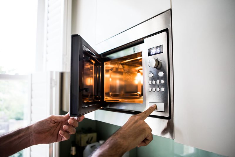 Someone lifting something out of a built-in microwave.