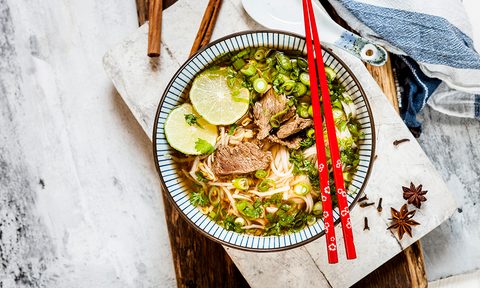 Bowl of Vietnamese Pho with rice noodles, mung beans, cilantro, spring onions and limes