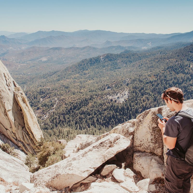 Man using his phone on a mountain.