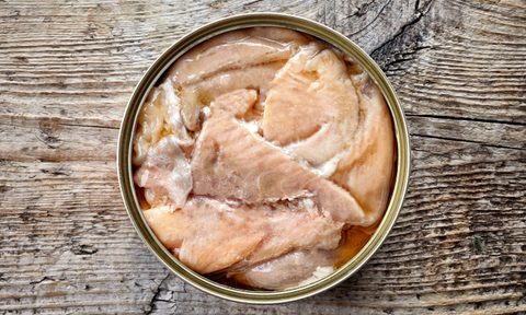Open tin can, canned salmon, on wooden background, top view