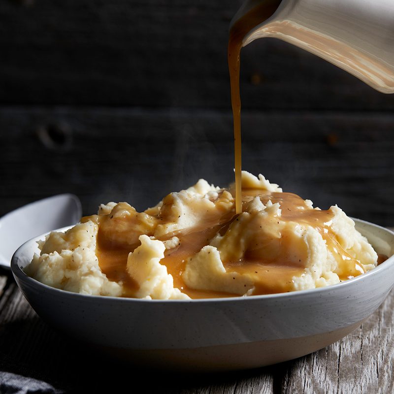 Pouring thick gravy on mashed potatoes