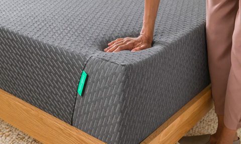 A hand pushing down on the Tuft and Needle Mint Mattress.